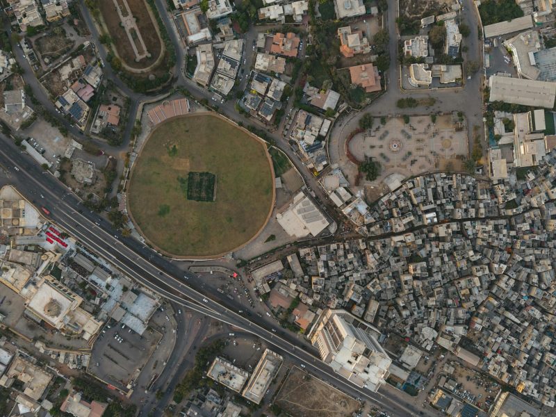 A detailed aerial shot of Karachi showing dense settlements and a distinct circular park, highlighting urban development.